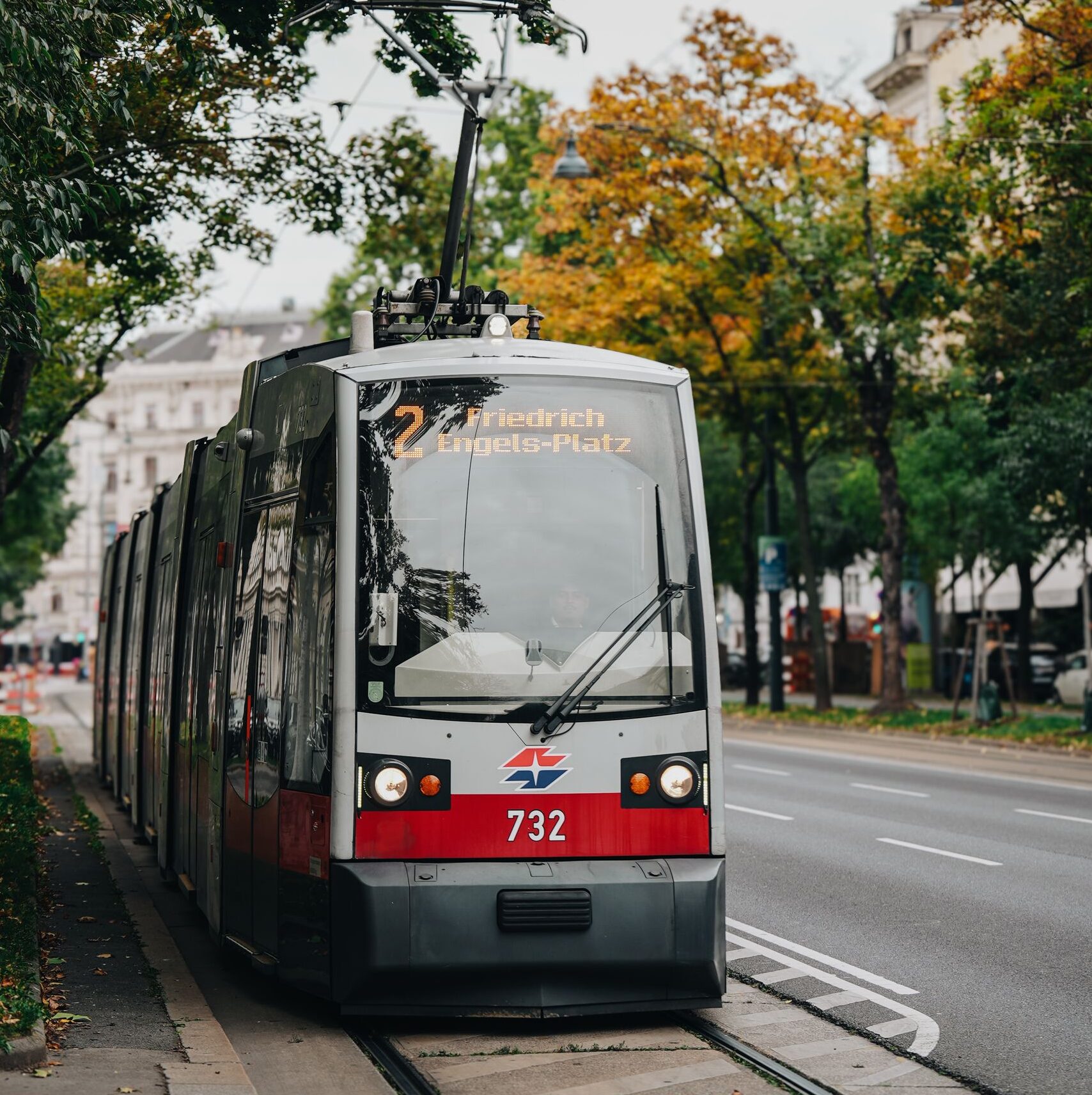 A tram travels through a tree-lined street in Vienna, Austria in autumn.
